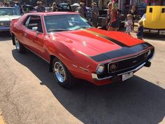 a red and black muscle car parked on the street