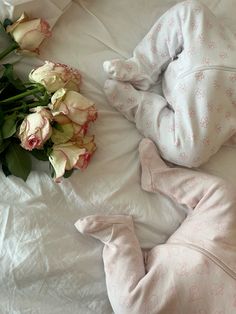 a baby sleeping on top of a bed next to flowers