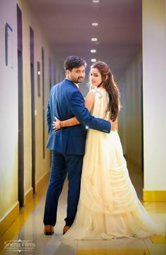 a man and woman in formal wear standing next to each other on a hallway way