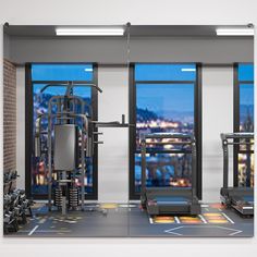 there is a gym with many machines in the room and windows overlooking the city at night