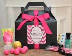 a black box with pink ribbon and some candy on the table in front of it