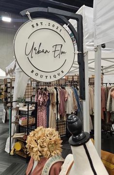 an open air market with clothing on racks and clothes hanging from the ceiling, in front of a sign that reads urban film boutique