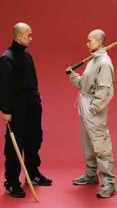 two men standing next to each other holding baseball bats