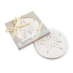 two white coasters with bows on them, one in the shape of a flower