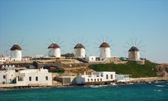 several windmills on top of a hill next to the ocean