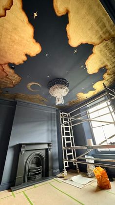 an empty room with a ladder and painting on the ceiling in front of a fire place