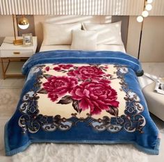 a bed covered in a blue blanket with pink flowers on it