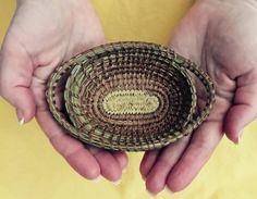 two hands holding a woven basket in front of a yellow background