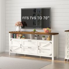 a flat screen tv sitting on top of a white entertainment center next to a wooden table