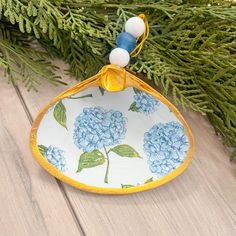 a blue and white flowered dish hanging from a tree