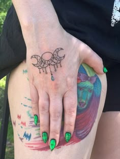 a woman's hand with green nail polish and tattoos on her left arm, next to a tattoo design