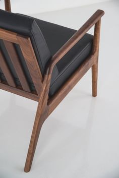 a wooden chair with black leather upholstered seat and backrest, on a white background