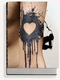 a man's arm with a heart and dripping paint on it, next to a black cat