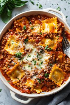 a white casserole dish filled with meat and cheese, topped with parsley