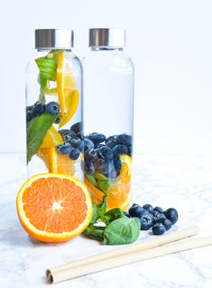 two glass bottles filled with oranges and blueberries