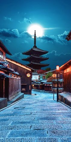 an empty street in the middle of a city at night with lanterns lit up on it