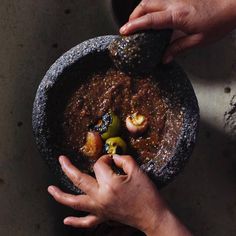 two hands reaching for some food in a bowl