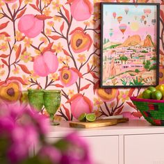 a colorful wallpapered room with fruit and vases on the dresser next to it