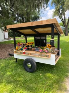 an outdoor food cart with sunflowers and flowers on it