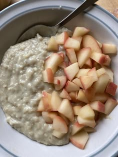 a bowl filled with oatmeal and apples on top of a wooden table