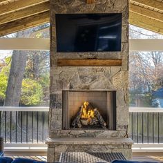 a stone fireplace with a flat screen tv above it and blue chairs around the fire place