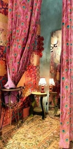 a room with pink curtains and a table in the corner next to a book shelf