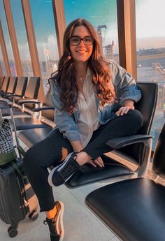 a woman is sitting in an airport waiting for her luggage to be picked off the plane