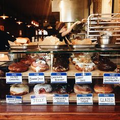 a display case filled with lots of doughnuts and pastries on top of wooden shelves