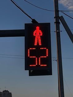 a red pedestrian crossing sign hanging from a pole