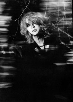 a black and white photo of a woman with her hair blowing in the wind,