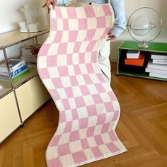 a woman holding up a pink and white checkered blanket