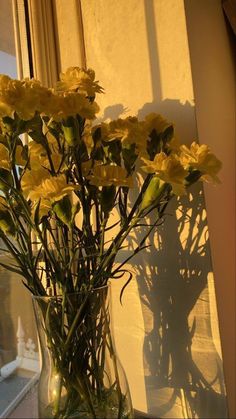 a vase filled with yellow flowers next to a window