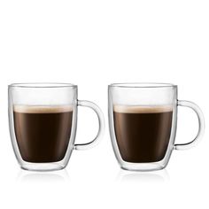 two coffee mugs sitting next to each other on a white surface with one cup filled with liquid