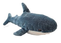 a stuffed shark is laying down on the white floor with it's mouth open