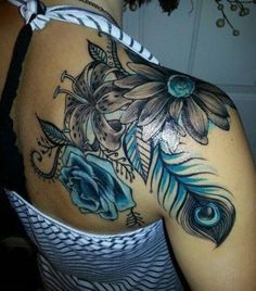 the back of a woman's shoulder with flowers and feathers on her left arm