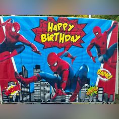 a spiderman birthday banner hanging on the side of a building with cityscape in the background