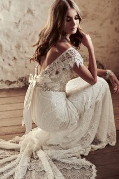 a woman in a white dress sitting on a wooden floor