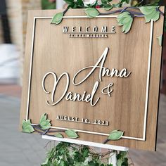 a wooden sign that says welcome to the bride and groom with greenery around it