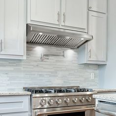 a stove top oven sitting inside of a kitchen next to white cupboards and drawers