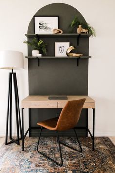 a desk with a lamp and some pictures on the wall above it, along with a chair