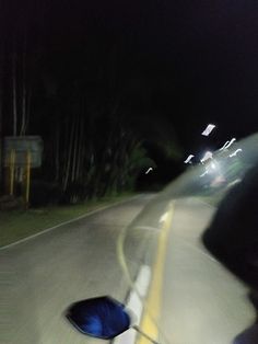 a person riding a bike down a street at night with an umbrella on the back