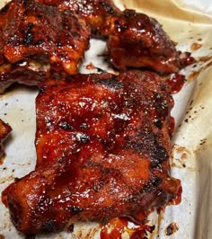 ribs covered in bbq sauce sitting on top of a piece of parchmented paper