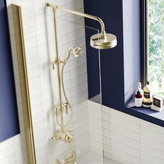 a bathtub and shower head in a bathroom with blue walls, white tile and gold fixtures