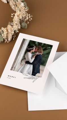 a wedding card with an image of a couple kissing on the forehead, and envelope next to it