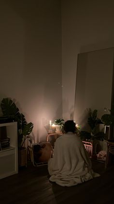 a person sitting on the floor in front of a mirror with their back turned to the camera