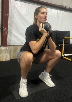 a woman squats on a mat in the gym