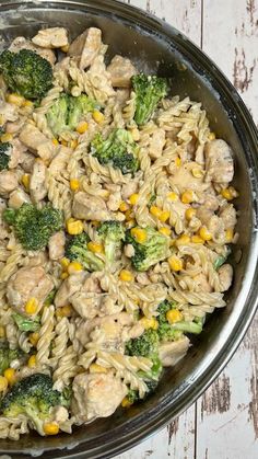 a bowl filled with pasta and broccoli on top of a wooden table