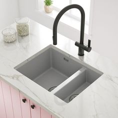 a kitchen sink sitting on top of a counter next to a potted green plant