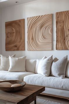 a living room with white couches and wooden wall art