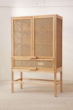 a wooden cabinet with wicker doors on the top and bottom, against a white wall